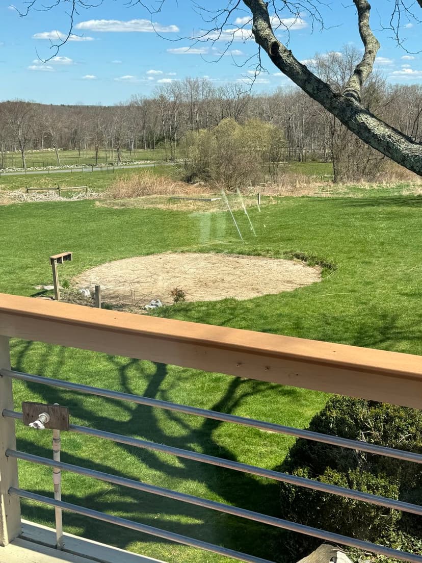 View from a balcony overlooking a circular garden area and lush green fields.